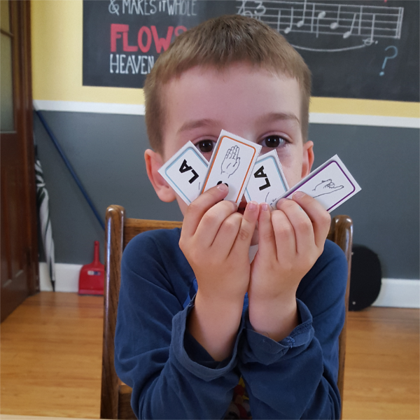 kid holding up mini solfège flashcards