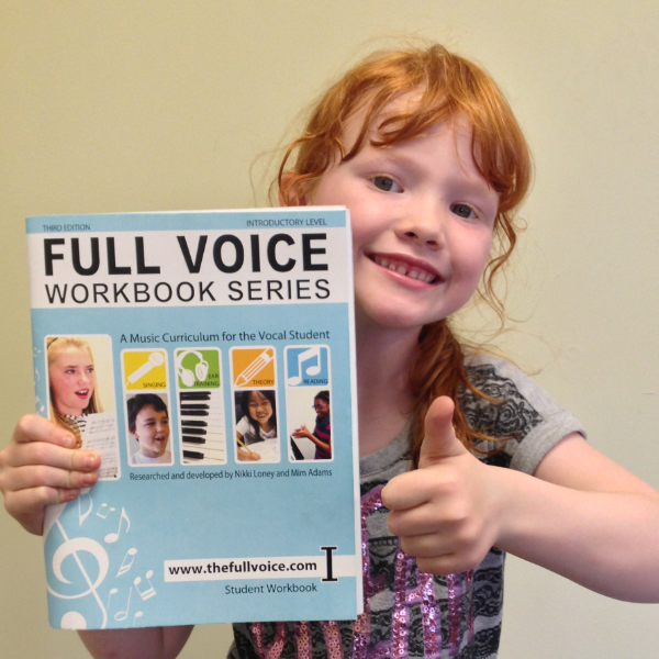 kid smiling and giving thumbs up holding Introductory Level workbook