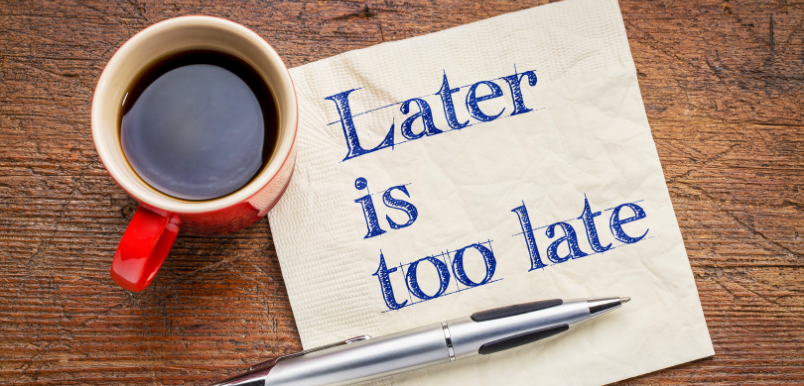 A coffee, pen, and napkin with "Later is too late" written on it.